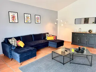 a living room with a blue couch and a table at Villa Louis - calme et spacieuse avec vue in Castelnaudary