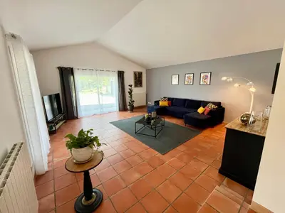 a living room with a blue couch and a tile floor at Villa Louis - calme et spacieuse avec vue in Castelnaudary