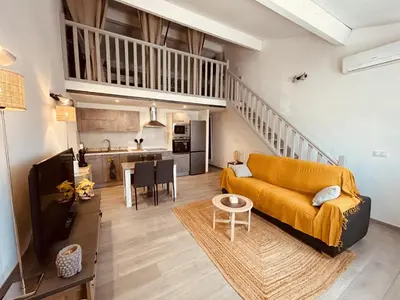 a living room with a yellow couch and a kitchen at LE PAOLO Appartement Deluxe in Narbonne