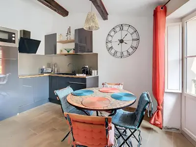 a kitchen with a table and chairs and a clock on the wall at Vue imprenable cité Carcassonne - 4 personnes in Carcassonne