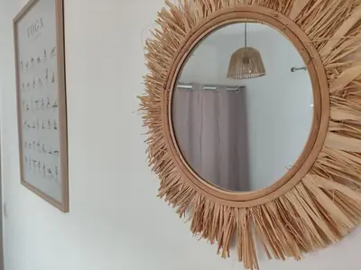a mirror with a rattan frame on a wall at Les flamants roses in Port-la-Nouvelle