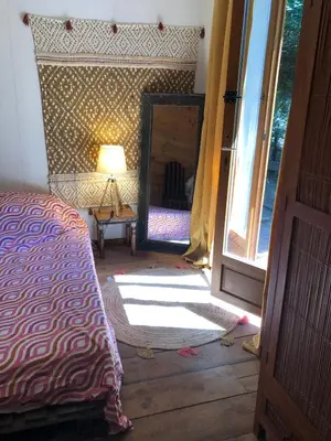 a bedroom with a mirror and a bed and a lamp at Le Jardin in Rennes-les-Bains