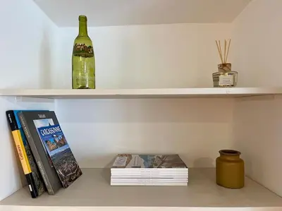 a shelf with a bottle of wine and books at La Tour de Guet in Carcassonne