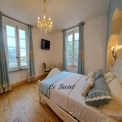 a bedroom with a bed with a chandelier and windows at La Maison du Canal - Homps - Le Sweet in Homps