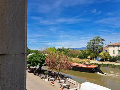a boat traveling down a river with a group of people at La Maison du Canal - Homps - Le Sweet in Homps