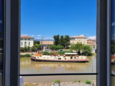 a boat on a river seen through a window at La Maison du Canal - Homps - Le Sweet in Homps