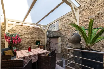 a patio with a table and chairs and a stone wall at Le Chardonneret Élégant - Maison pour 4 climatisée in La Livinière