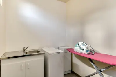 a small kitchen with a pink table and a sink at Le Chardonneret Élégant - Maison pour 4 climatisée in La Livinière
