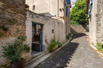 an alley with a blue door on a building at Le Chardonneret Élégant - Maison pour 4 climatisée in La Livinière