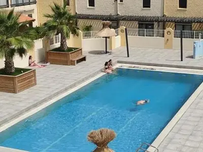a large blue swimming pool with people sitting around it at Duplex T4 Confort 6 Pers., Piscine, Parking, Centre Port à Gruissan - FR-1-796-74 in Gruissan