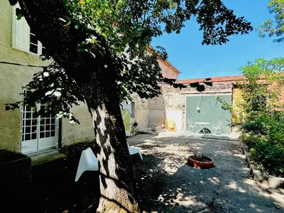 a yard with a tree and two white chairs at Maison de campagne Arty entièrement rénovée 4 chambres in Roquecourbe