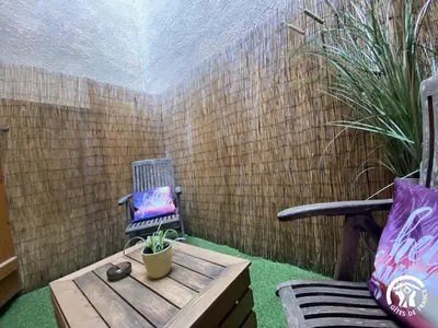 a small patio with a wooden table and a chair at Grenache rdc in Fosse