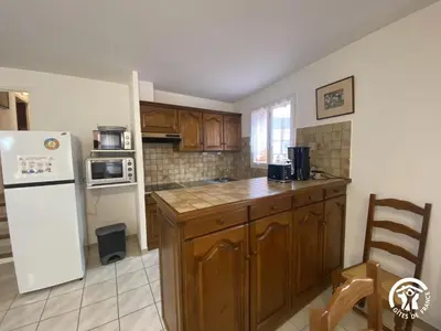 a kitchen with wooden cabinets and a white refrigerator at Grenache rdc in Fosse