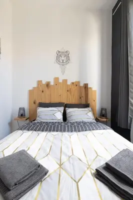 a bedroom with a large bed with a wooden headboard at Le 107 CARCA ! in Carcassonne