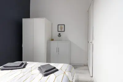 a bedroom with white cabinets and a bed with two towels at Le 107 CARCA ! in Carcassonne