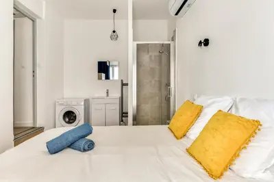 a white bed with two pillows and a washing machine at Le Logis de Joseph au pied de la Cité Médiévale in Carcassonne