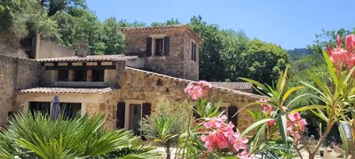 an old stone house with pink flowers in the foreground at Magnifique Mas avec Piscine - La Bergerie du Razès in Alet-les-Bains