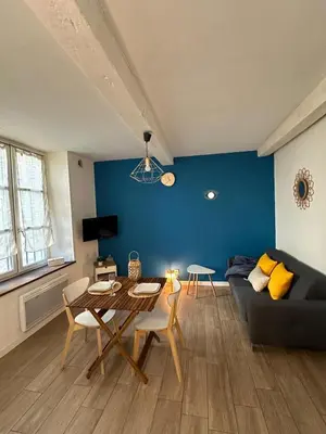 a living room with a table and a blue wall at Bulles de bonheur - Carcassonne in Carcassonne