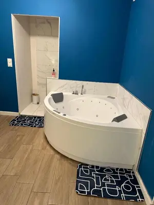 a white bath tub in a bathroom with a blue wall at Bulles de bonheur - Carcassonne in Carcassonne