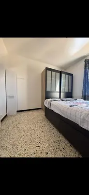 a bedroom with a bed and a refrigerator in it at T2 moderne à 2 min de la plage in Port-la-Nouvelle