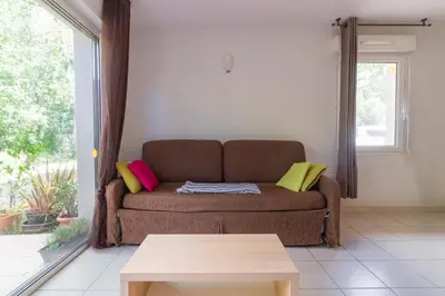 a living room with a brown couch with colorful pillows at Douceur de Jouarres - Avec piscine in Azille