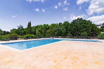 a swimming pool with a tile patio and trees at Douceur de Jouarres - Avec piscine in Azille