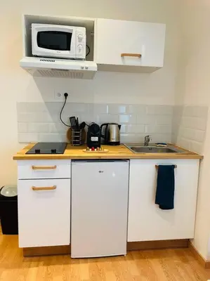 a kitchen with white cabinets and a microwave on a counter at Studio Charles de Gaulle II in Castres