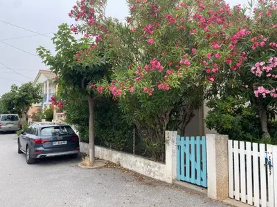 a car parked next to a fence with pink flowers at Maison 300 m de la plage avec un bel extérieur in Gruissan