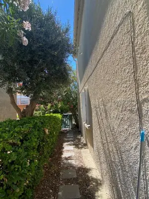 a side walk next to a wall with a hedge at Maison 300 m de la plage avec un bel extérieur in Gruissan