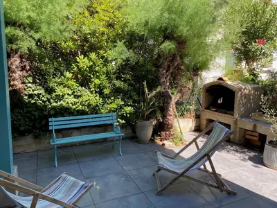 two chairs and a bench sitting on a patio at Maison 300 m de la plage avec un bel extérieur in Gruissan