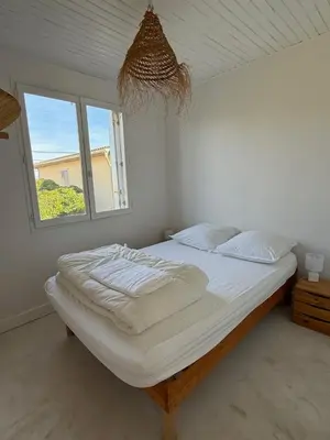 a bedroom with a large bed with a window at Maison 300 m de la plage avec un bel extérieur in Gruissan