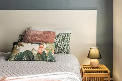 a bedroom with a king sized bed with tropical pillows at Le Cocon Urbain in Narbonne
