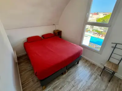 a red bed in a small room with a window at L'appart B42 in Gruissan
