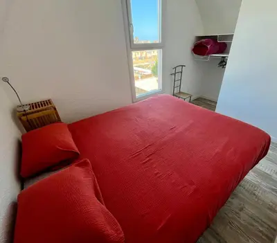 a red bed in a room with a window at L'appart B42 in Gruissan