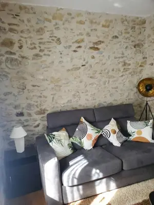 a couch in a living room with a stone wall at Charmante Petite Maison Audoise in Trausse