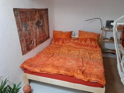 a bedroom with a bed with an orange comforter at La Petite Tour de Puivert in Puivert