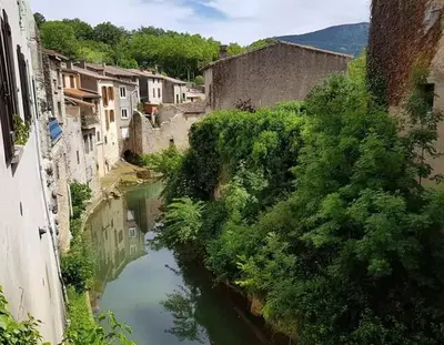 a view of a river in a town with buildings at La Petite Tour de Puivert in Puivert