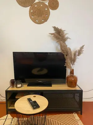 a television on a stand with a table and a remote control at T2 climatisé - Près des plages in Narbonne