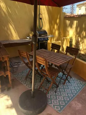 a table and chairs under an umbrella on a patio at Grand T2 climatisé avec jardin et spa in Narbonne