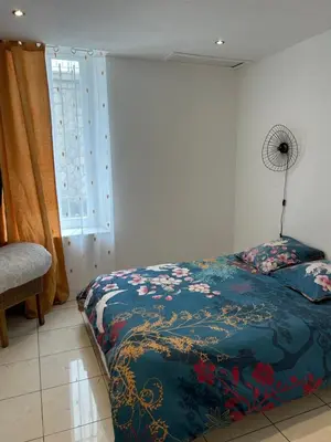 a bedroom with a bed with a blue comforter and a window at Grand T2 climatisé avec jardin et spa in Narbonne