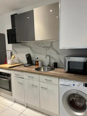 a kitchen with a sink and a washing machine at Grand T2 climatisé avec jardin et spa in Narbonne