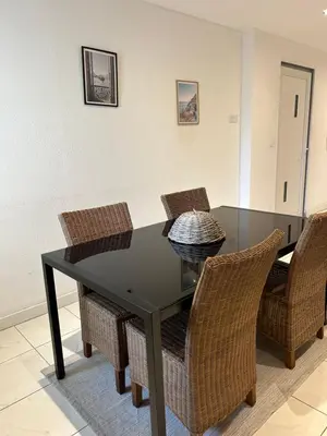 a black dining room table with wicker chairs at Grand T2 climatisé avec jardin et spa in Narbonne