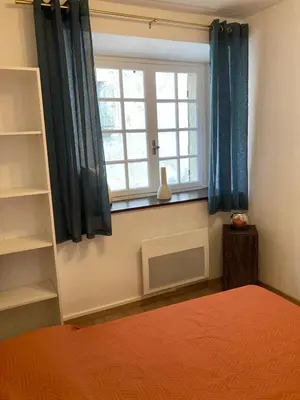 a bedroom with a bed and a window with blue curtains at Maison 2 chambres avec cour intérieure in Alet-les-Bains