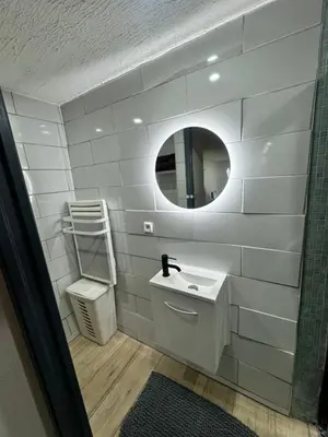 a white bathroom with a sink and a mirror at Charmante maison de village in Bram