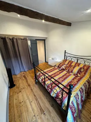a bedroom with a bed and a wooden floor at Charmante maison de village in Bram