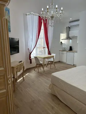 a bedroom with a bed and a table and a kitchen at Studio Cosy du Cloitre in Narbonne