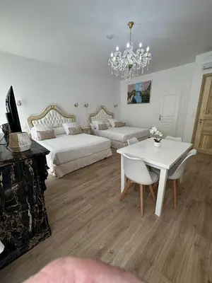 a bedroom with two beds and a table and a chandelier at Studio familial du Cloitre in Narbonne