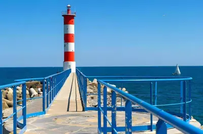 a red and white lighthouse on the side of the ocean at Le Mieukerien - Réserve africaine 15 mn - Plage 200 m in Port-la-Nouvelle
