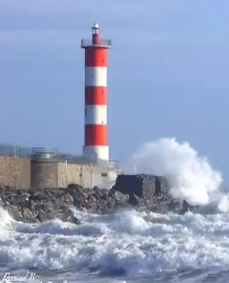 a red and white lighthouse in the ocean with waves at Le Mieukerien - Réserve africaine 15 mn - Plage 200 m in Port-la-Nouvelle
