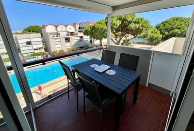 a balcony with a table and chairs and a pool at L'appart D79 in Gruissan